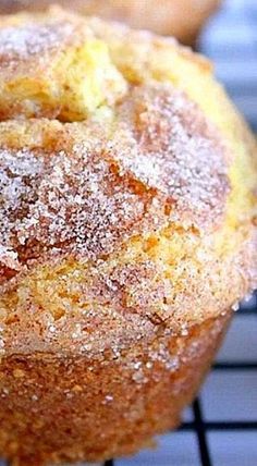 a muffin with powdered sugar on top sitting on a cooling rack next to other muffins