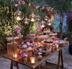 a table topped with lots of cakes and desserts next to candles in vases