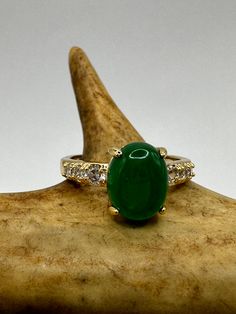 vintage green fun jade ring  Setting is a golden finished bronze setting  This is one of my hand re finished treasures. Salvaged from vintage.  Size   7 Re sizing can be done for a $20 fee and may take up to a week.  Engraving is $4 per letter.  Thank you for supporting a veteran's small business. All jewelry is shipped free within the US in a stylish gift box Fine Jewelry Emerald Green Oval Cabochon Ring, Green Oval Cabochon Emerald Ring, Fine Jewelry Green Oval Cabochon Rings, Green Emerald Oval Cabochon Ring, Green Emerald Ring With Oval Cabochon, Luxury Emerald Ring With Oval Cabochon Center Stone, Emerald Ring With Oval Cabochon Center Stone, Emerald Oval Cabochon Ring With Center Stone, Oval Cabochon Emerald Ring With Center Stone