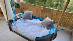 a bed that has some pillows on it and is hanging from a rope over the floor