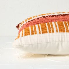 an orange and white striped pillow sitting on top of a table