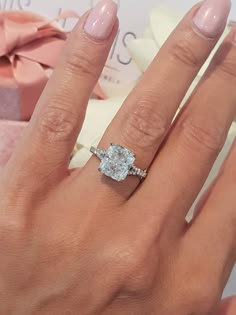 a woman's hand with a ring on it and a gift box in the background