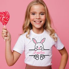 "Treat your little one to their very own personalised Easter outfit this year! This gorgeous t-shirt/baby bodysuit has a beautiful hand designed Bunny Split Monogram motif on the front. Your little ones will look super cute in their little bunny t-shirt or baby vest/ Perfect gift for kids this Easter. Add a special touch with this stylish tee. - unisex - made from 100% cotton - soft and comfortable SIZE GUIDE: T-shirts: 1/2* -24\" 2/3 -25\" 3/4 -26\" 5/6 -28\" 7/8 -30\" 9/11 -32\" 12/13 -34\" 14/15 -36\" Baby bodysuits: 0-3 months - 12lbs 2.7 kg | 3-6 months 18lbs8kg | 6-9 months 21lbs 9.5kg | 9-12 months 44lbs 11kg | 12-18 months 80cm-86cm | 18-24 months 86cm-92cm All items are handmade with love 💗💙 Please ensure you purchase the correct size as we do not accept returns if the incorrect Customizable Cute White T-shirt, Cute T-shirt With Name Print For Gift, Customizable White T-shirt For Personalized Gift, Cute Personalized White Tops, Cute Personalized Crew Neck T-shirt, Personalized White Top With Name Print, Personalized Name Print White Top, Playful Personalized White Tops, Playful White Customizable T-shirt