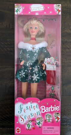 the barbie doll is wearing a green dress with white fur collar and she has blonde hair