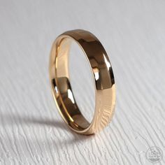 a gold wedding ring sitting on top of a white table