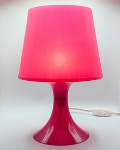 a bright pink lamp with a white cord plugged in to it's base