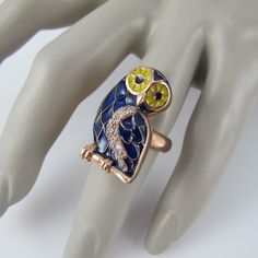 A sterling stunner with plique-a-jour enamel and glittering CZ stones, this size 7 ½ statement ring is certain to get you noticed. Done in a copper overlay that really sets of the cobalt blue body, the Barn Owl also boasts yellow on its face with red in its eyes, while the CZs are perfectly placed to accent its wing. The Bird measures 1 1/8 inches in length and is 5/8 inch wide. It is in excellent, new condition and marked Sezgin, 925 inside the band. Enamel Multi-stone Ring, Enamel Multi-stone Rings As A Gift, Fine Jewelry Enamel Ring Hallmarked, Multi-stone Enamel Ring Jewelry, Enamel Inlay Jewelry For Anniversary, Multi-stone Enamel Ring, Round Multi-stone Enamel Jewelry, Round Jeweled Enamel Jewelry, Gold Multi-stone Enamel Jewelry