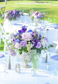 a vase filled with purple and white flowers on top of a table next to chairs