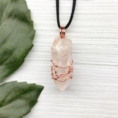 Natural Clear Quartz Necklace. Raw Clear Quartz crystal hand wrapped with 99.9% pure copper wire that is tarnish resistant. Comes on a black satin lobster clasp necklace. You get the exact pendant pictured.  Pictures are taken close up. Exact pendant measurement is 1.8 Inches H X 0.6 Inches W. This Clear Quartz is from Brazil. ✨ Pendant made during the Moon in Pisces. ✨ Items included with purchase- -Raw Clear Quartz copper pendant on a black lobster clasp necklace. -Drawstring pouch. -Handmade crystal info card. *Photo props not included* ✨ *Quartz Associations* Astrological Signs- All. Planets- Moon and Sun. Chakras- All. Elements- Fire and Water. ✨ This is a natural raw crystal. It has not been polished or tumbled. I try to photograph/video every color variation on the crystal so you kn Rose Gold Copper Wire Necklace For Gift, Rose Gold Copper Wire Necklace Gift, Rose Gold Hand Wrapped Necklace Gift, Electroformed Crystal Necklace With Copper Wire, Handmade Adjustable Copper Wire Crystal Necklace, Handmade Adjustable Copper Wire Crystal Necklaces, Handmade Adjustable Crystal Necklace With Copper Wire, Handmade Adjustable Crystal Necklaces With Copper Wire, Spiritual Rose Gold Wire Wrapped Necklaces