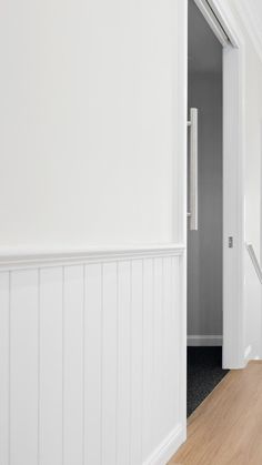 an empty hallway with white walls and wood floors