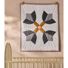 a quilt hanging on the wall above a crib