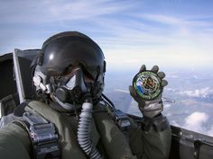 a fighter jet flying through the sky next to an air force pilot holding a badge