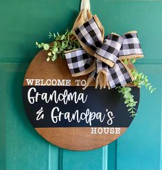 welcome to grandma and grandpa's house sign hanging on the front door with greenery