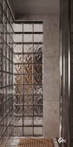 a glass block wall in a bathroom next to a shower stall with a wooden mat on the floor