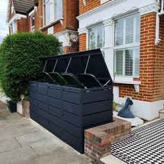 a large black box sitting on the side of a road next to a building with white windows