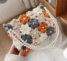 a woman is holding a purse made out of crocheted flowers and pearl beads