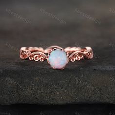 a white opal stone is set in an intricate rose gold band