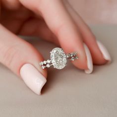 a woman's hand holding an engagement ring with diamonds on the middle of it