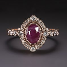 an oval shaped ruby and diamond ring on a black surface with white diamonds around it