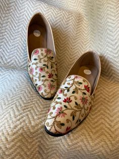 pair of shoes with flowers on them sitting on a bed