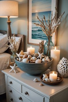 a bowl filled with seashells and candles on top of a dresser next to a bed