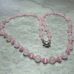 Graduated beads of alternative Rose pink Quartz beads and pink Glass Cat's Eye beads feature in this soft pink necklace. At each end of the necklace the Rose Quartz beads are 6mm with 4mm Cat's Eye beads while in the middle we have 8mm Rose Quartz beads and 6mm Glass Cat's Eye beads. The necklace has a Platinum plated Brass magnetic clasp and comes with free matching earrings with Silver plated Stainless Steel earwires. Necklace and Earrings come contained within an organza bag. Rose Quartz has a very soothing, comforting energy and can help heal pain, grief and heartbreak. Its energy is accepting, nurturing, generous and kind. It comforts when you feel broken or weary helping you accept and nurture yourself. A crystal of unconditional love. It carries an energy of compassion, comfort, hea Elegant Pink Necklaces With 8mm Beads, Pink Necklaces With 8mm Beads, Pink 8mm Beaded Necklace, Pink Hand-strung Round Bead Necklaces, Pink Hand-strung Round Beads Necklace, Pink Rose Quartz Gemstone Beaded Necklaces, Elegant Pink Beaded Necklaces With 8mm Beads, Pink Rose Quartz Gemstone Beaded Necklace, Elegant Pink Beaded Necklace With 8mm Beads