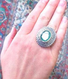 a woman's hand holding a ring with an oval shaped stone in the middle