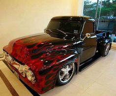 a black and red truck with flames on it's hood parked in a room