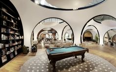 a pool table in the middle of a room with many bookshelves and couches