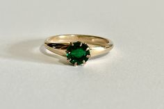 Gorgeous vintage 10k yellow gold simulated emerald ring, circa 1900s! This stylish Edwardian ring showcases a green glass simulated emerald in 'crown' style eight-prong mounting. The beautiful deep green glass is round cut. Stunning piece of fine vintage jewelry featuring May's birthstone color, circa 1900s!  ERA - Circa 1900s, Edwardian Era METAL / MATERIAL - 10k yellow gold, green glass MARKINGS / HISTORY - Inside of band is marked with Trade Mark CONDITION - Good antique condition. Glass may have chips & scratches and is securely prong set.  SIZE / MEASUREMENTS - Size: 10, Simulated emerald: 7 mm, Rise off the finger 5.1 mm, Band: tapers to 2.5 mm, Weight: 2.62 grams https://www.etsy.com/shop/LastCenturyJewels Heirloom Emerald Ring Stamped 14k, Heirloom 14k Stamped Emerald Ring, Antique Emerald Ring In Stamped 14k Yellow Gold, Antique Green Emerald Ring With Prong Setting, Antique 14k Gold Emerald Ring, Antique Emerald Ring In 14k Gold, Victorian Emerald Ring In Yellow Gold Stamped 14k, Victorian Emerald Ring In 14k Yellow Gold, Art Deco Emerald Ring With 17 Jewels