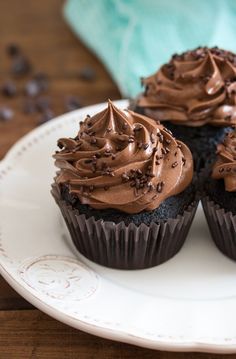 three cupcakes with chocolate frosting on a plate