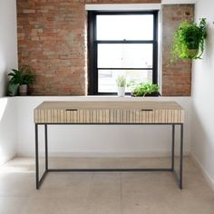 a table with two plants on it in front of a brick wall and windowsill