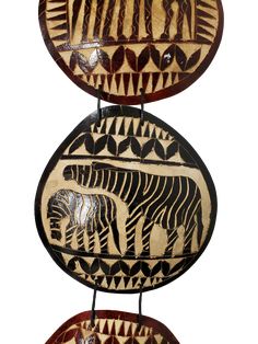 two decorative plates with zebras and elephants painted on the sides, hanging from metal rods