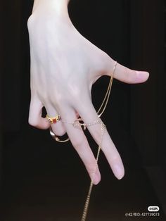 a woman's hand with several rings and chains on it, all in gold