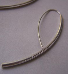 "Beautiful simple contemporary earrings of minimal design that will look great with a casual outfit, as well as a more formal one. I formed a 2 mm. sterling silver wire to a graceful curve and soldered a .7 mm. ear wire for a simple, minimalist, and fashionable look. I will include a pair of silicone backs for safety. Length: now you can pick your favorite length by clicking on the drop down bar under the price. Your choice of 2\" (as pictured above), 1 3/4\", or 1 1/2\" Ear wire: 21 Ga (0.7mm)" Contemporary Earrings, Threader Earrings, Minimalist Earrings, Ear Wire, Minimal Design, Silver Wire, Casual Outfit, Bangles, Bar