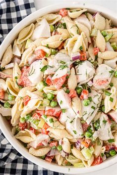 a white bowl filled with pasta salad on top of a checkered table cloth