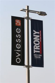 two black and white banners hanging from a light pole in front of a blue sky