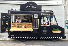 two men are behind the counter of a food truck