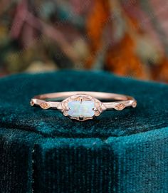 a white opal ring sitting on top of a velvet box