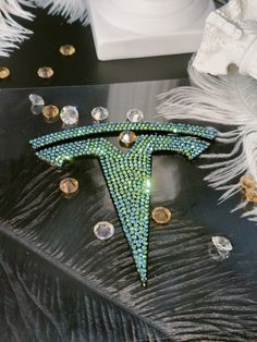 a green brooch sitting on top of a black table next to feathers and beads