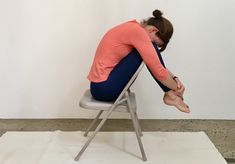 a woman is sitting on a chair with her head in her hands while she stretches