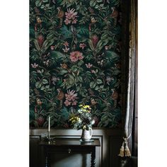 a vase with flowers on top of a table in front of a floral wallpaper