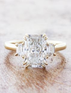 an engagement ring with a cushion cut diamond and baguettes on the side, set in yellow gold