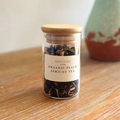 a jar filled with organic peach tea sitting on top of a wooden table next to a vase