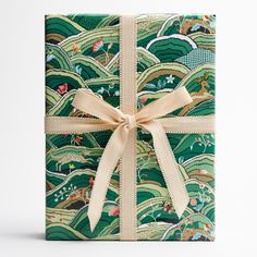 a gift wrapped in green and gold paper with a bow