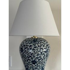 a blue and white vase sitting on top of a table next to a lampshade