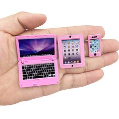 three small pink laptops in the palm of a person's hand with an iphone