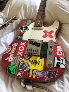 an electric guitar covered in stickers on a bed