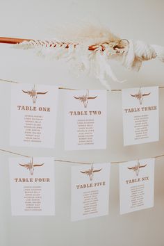 wedding seating cards hanging from a rope with longhorns on them and table numbers