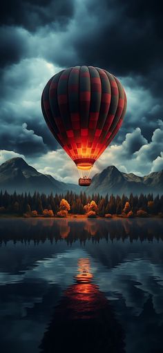 a hot air balloon flying over a lake under a cloudy sky